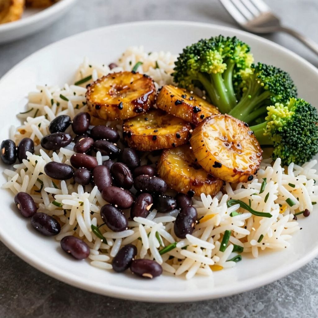 A healthy vegetarian bowl featuring white rice, black beans, caramelized plantains, and steamed broccoli florets.